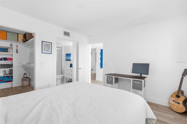 bedroom featuring connected bathroom and light wood-type flooring