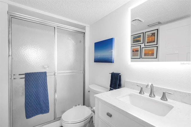 bathroom featuring toilet, vanity, an enclosed shower, and a textured ceiling