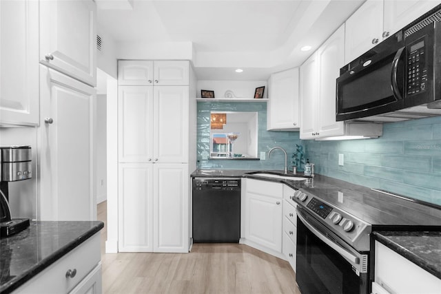 kitchen with black appliances, dark stone counters, light hardwood / wood-style floors, and white cabinets