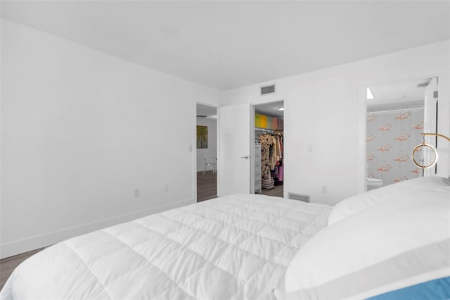 bedroom featuring a closet, a walk in closet, hardwood / wood-style flooring, and ensuite bathroom