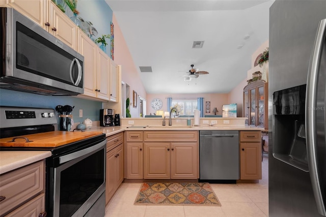 kitchen with lofted ceiling, ceiling fan, stainless steel appliances, and light tile patterned floors