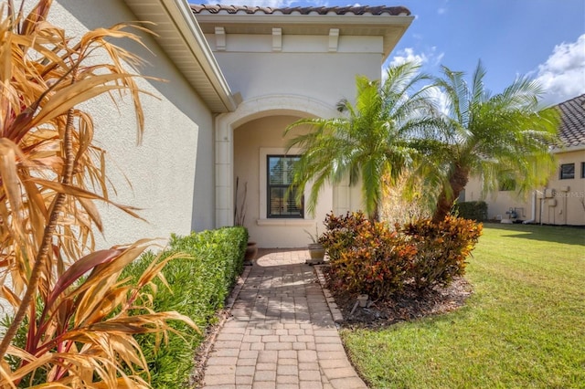 view of exterior entry featuring a lawn