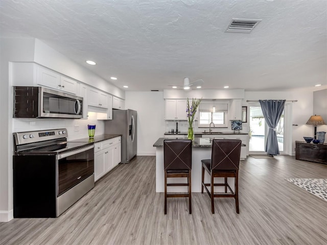 kitchen featuring white cabinets, sink, stainless steel appliances, and light hardwood / wood-style flooring