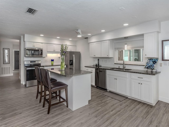 kitchen featuring a center island, sink, ceiling fan, white cabinetry, and stainless steel appliances