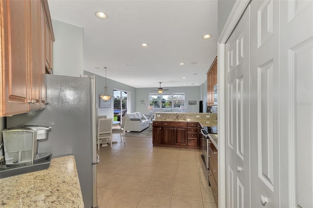 kitchen featuring hanging light fixtures, electric range, ceiling fan, light tile patterned flooring, and sink