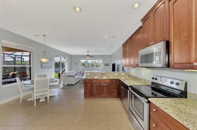 kitchen featuring kitchen peninsula, light tile patterned floors, appliances with stainless steel finishes, sink, and decorative light fixtures