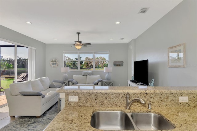 kitchen featuring ceiling fan, light tile patterned flooring, light stone countertops, and sink