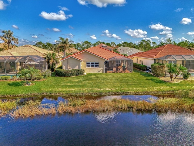 back of property with a lanai, a yard, and a water view