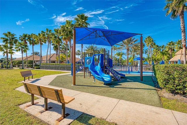 view of play area featuring a lawn and a pool