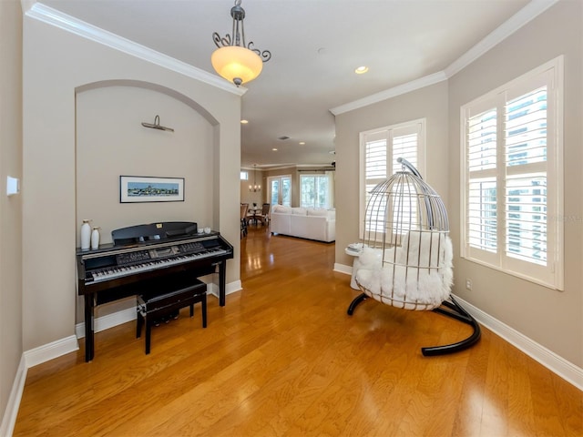 living area with crown molding and light hardwood / wood-style flooring