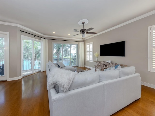 living room with hardwood / wood-style flooring, ceiling fan, and ornamental molding