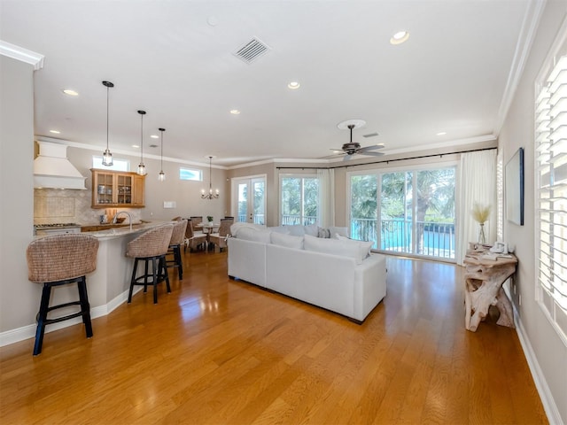 living room with light wood-type flooring, crown molding, and a healthy amount of sunlight