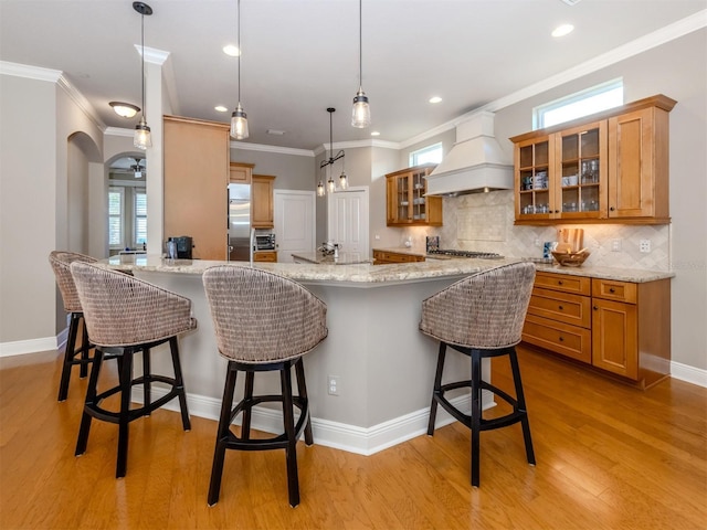 kitchen featuring a breakfast bar, light hardwood / wood-style flooring, plenty of natural light, and custom exhaust hood