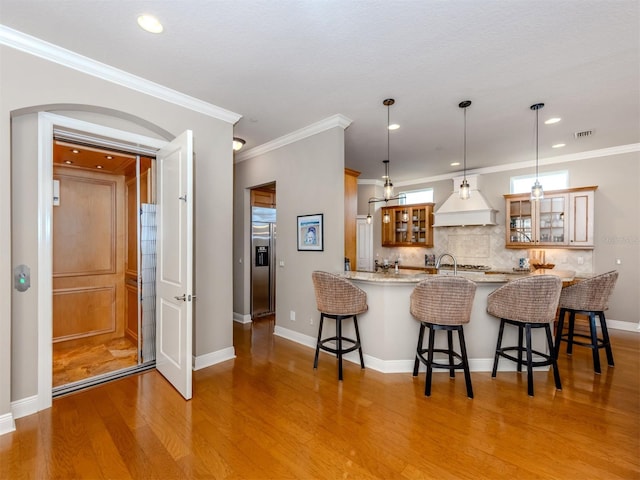 kitchen featuring kitchen peninsula, crown molding, a breakfast bar, and light wood-type flooring