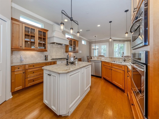 kitchen featuring a center island, premium range hood, light hardwood / wood-style flooring, decorative light fixtures, and stainless steel appliances