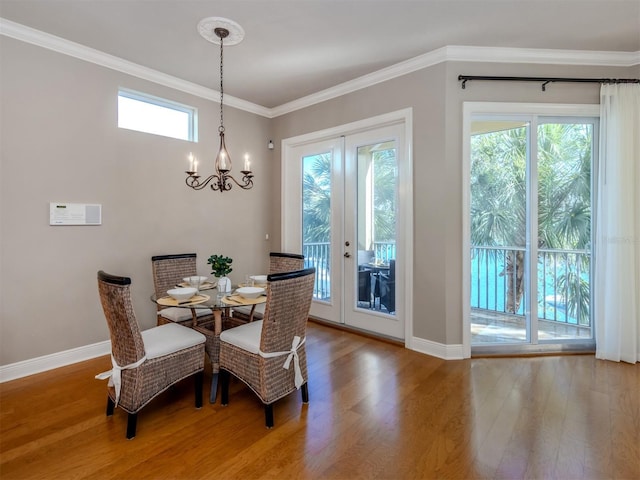 dining space featuring hardwood / wood-style flooring, a notable chandelier, a healthy amount of sunlight, and ornamental molding