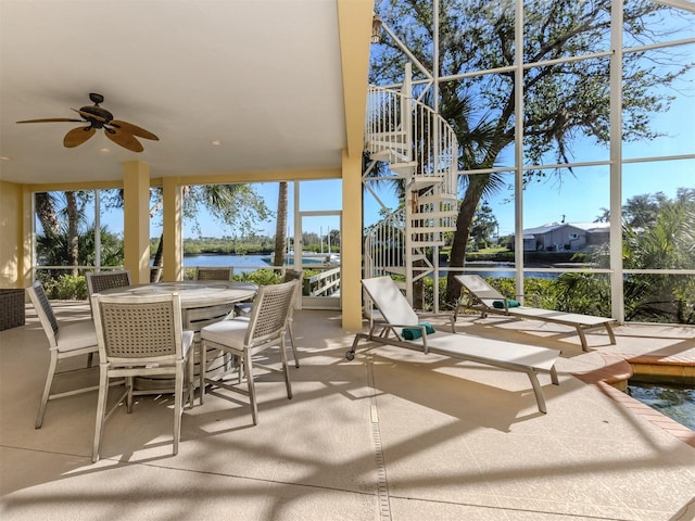 sunroom / solarium featuring ceiling fan and a water view