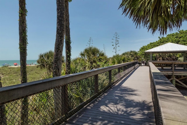 view of dock with a gazebo, a water view, and a view of the beach