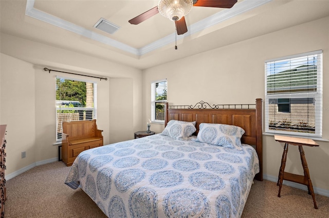 bedroom featuring ceiling fan, a raised ceiling, multiple windows, and light colored carpet