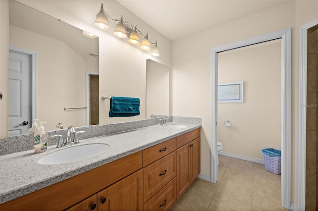 bathroom with toilet, vanity, and tile patterned floors