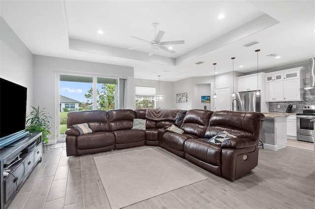 living room featuring light hardwood / wood-style floors, a tray ceiling, and ceiling fan