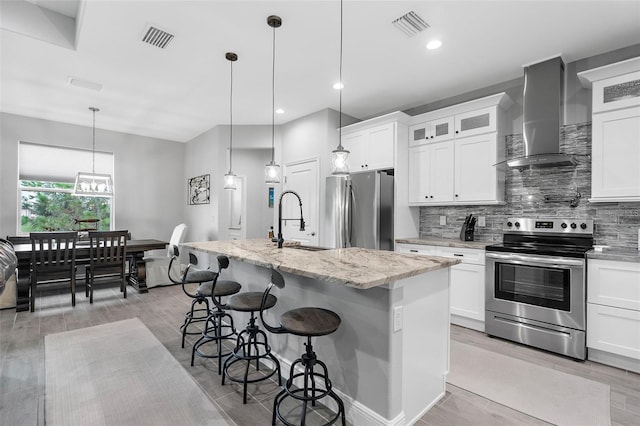 kitchen featuring appliances with stainless steel finishes, light hardwood / wood-style flooring, a kitchen island with sink, and white cabinetry