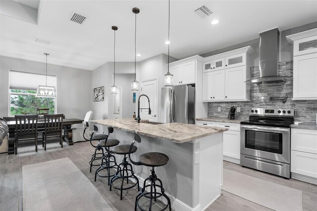 8559 Waldrep St, Port Charlotte, FL 33981 - kitchen with stainless steel appliances, wall chimney range hood, a sink, a center island with sink, and tasteful backsplash