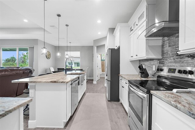 8559 Waldrep St, Port Charlotte, FL 33981 - kitchen with stainless steel appliances, wall chimney exhaust hood, light wood-style flooring, backsplash, and a breakfast bar area