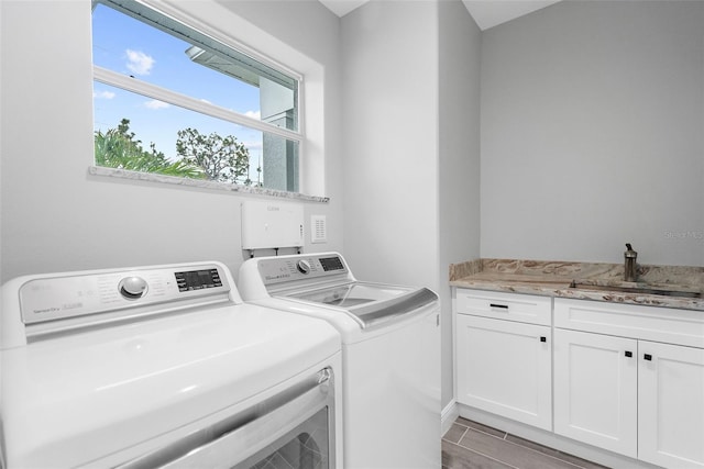 laundry area with cabinets, sink, washer and clothes dryer, and light wood-type flooring