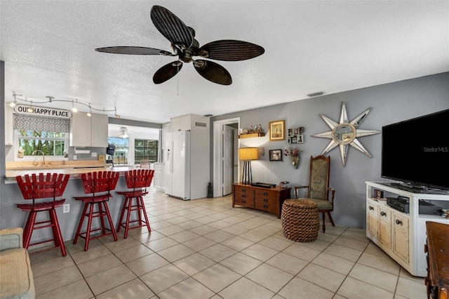 living room featuring sink, a textured ceiling, and light tile patterned flooring