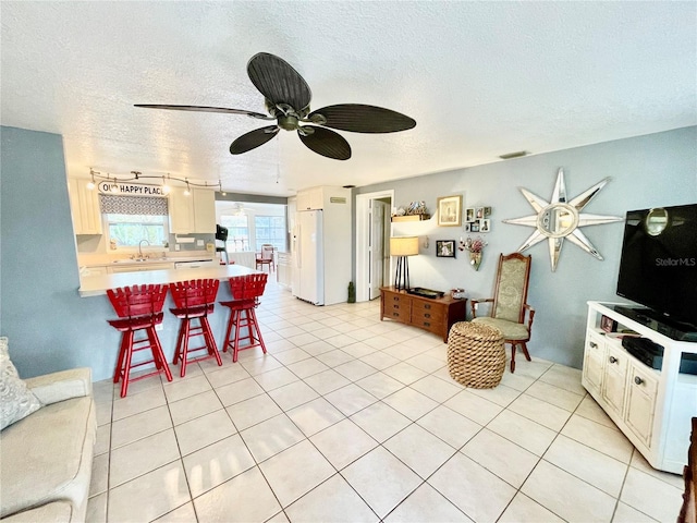 living room with light tile patterned floors, a textured ceiling, and sink