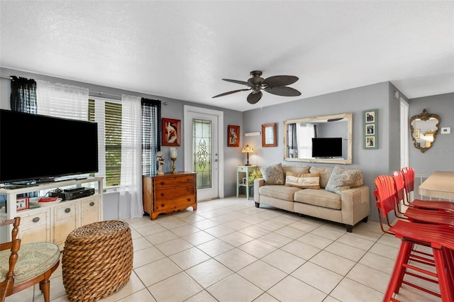 living room featuring ceiling fan, light tile patterned floors, and a textured ceiling