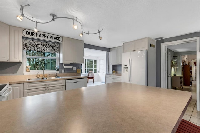 kitchen with white cabinetry, sink, rail lighting, a textured ceiling, and white appliances