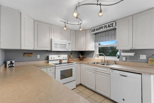 kitchen with sink, rail lighting, light tile patterned floors, white appliances, and white cabinets