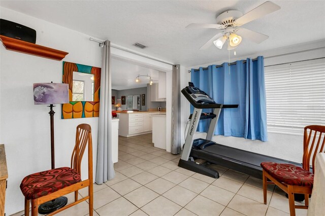 workout room with ceiling fan, plenty of natural light, light tile patterned floors, and a textured ceiling