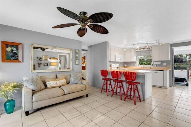 living room with ceiling fan, sink, light tile patterned floors, and a textured ceiling