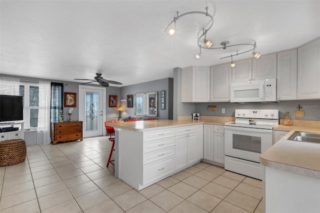 kitchen featuring kitchen peninsula, white cabinetry, light tile patterned floors, and white appliances