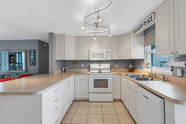 kitchen featuring kitchen peninsula, white appliances, sink, light tile patterned floors, and white cabinets