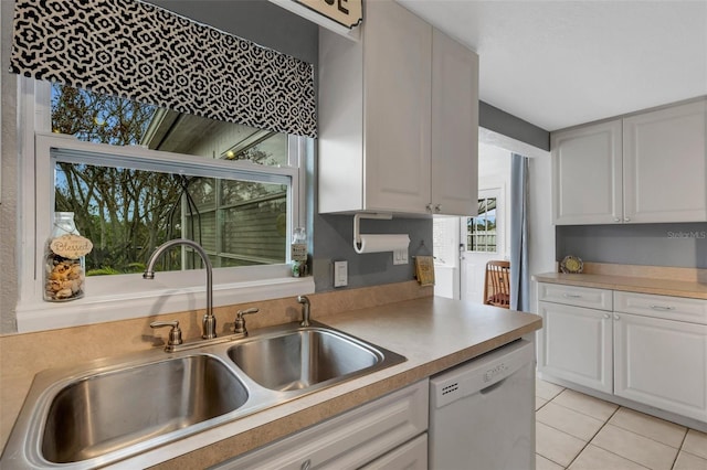 kitchen with dishwasher, light tile patterned floors, white cabinets, and sink