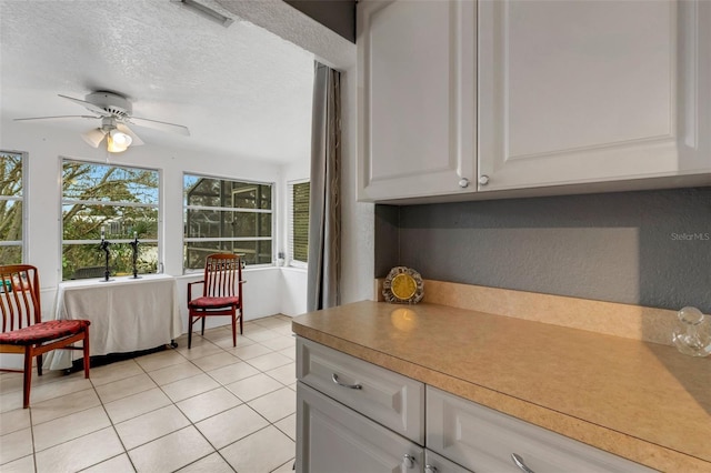 kitchen featuring ceiling fan, light tile patterned floors, white cabinets, and a textured ceiling