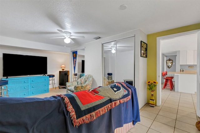 tiled bedroom featuring ceiling fan, a closet, and a textured ceiling