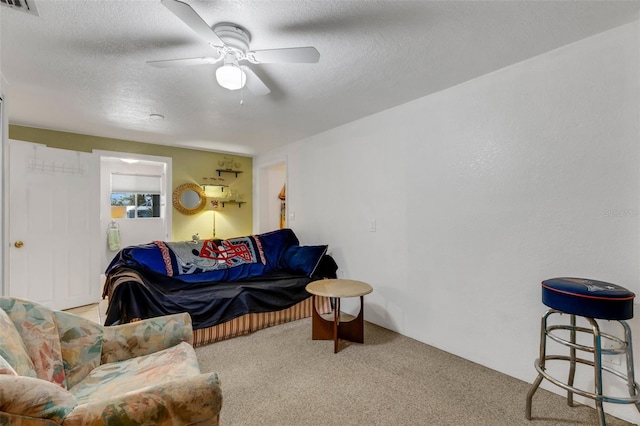 carpeted living room featuring ceiling fan and a textured ceiling