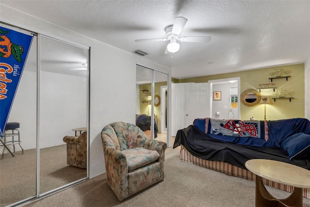 living room with ceiling fan, carpet floors, and a textured ceiling