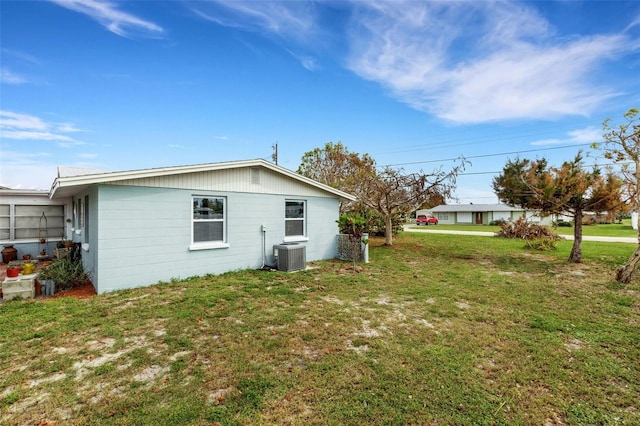 view of side of home featuring central AC unit and a lawn