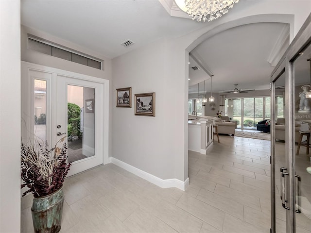 tiled entryway with ceiling fan with notable chandelier