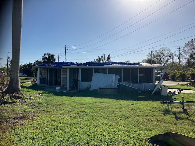 back of property with a sunroom and a lawn