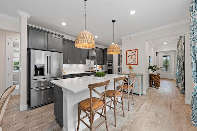 kitchen featuring decorative light fixtures, stainless steel appliances, a center island with sink, and a wealth of natural light