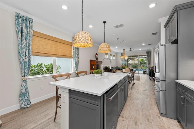 kitchen with gray cabinets, an island with sink, light hardwood / wood-style flooring, and stainless steel appliances