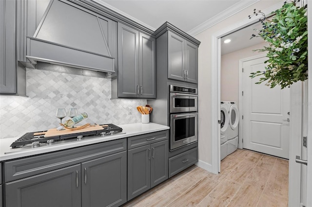 kitchen featuring premium range hood, light hardwood / wood-style flooring, independent washer and dryer, gray cabinetry, and crown molding