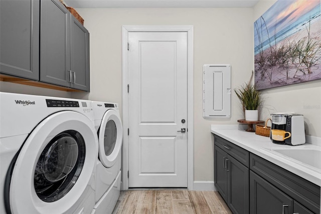 washroom featuring independent washer and dryer, cabinets, and light hardwood / wood-style flooring